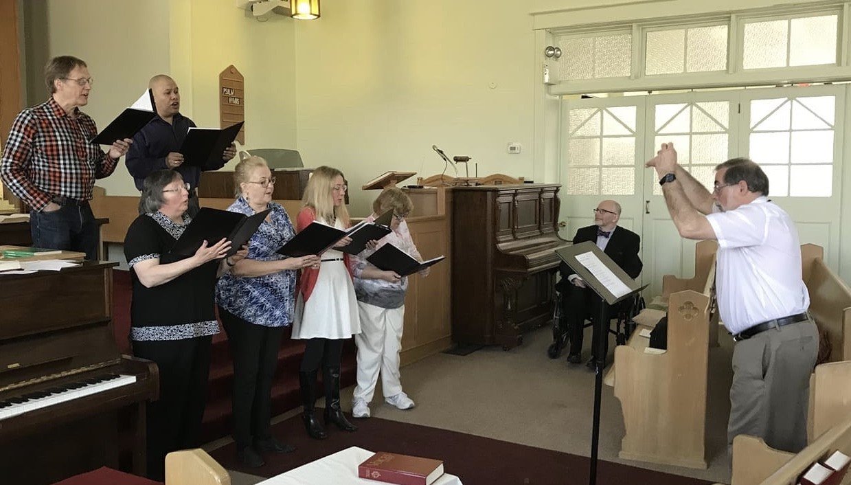 The choir practicing inside the sanctuary at Wesley United Church in Stoney Creek, Ontario, led by the music director.